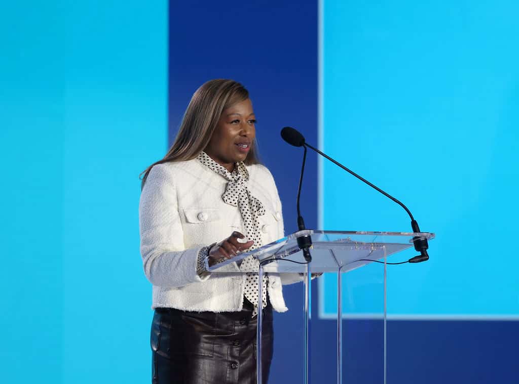 MassBio Board Chair Tamar Thompson speaking at a transparent podium wearing a white blazer during the State of Possible Conference.